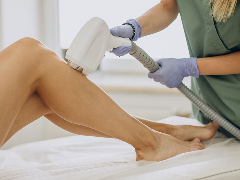 Na imagem está presente uma mulher realizando depilação a laser nas pernas.